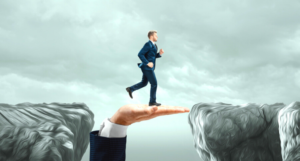 man walking across a hand to the next cliff